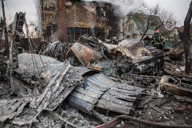 A Ukrainian firefighter walks between fragments of a downed aircraft seen in in Kyiv, Ukraine, on Feb. 25, 2022. Russia was pressing its invasion of Ukraine to the outskirts of the capital after unleashing airstrikes on cities and military bases and sending in troops and tanks from three sides. (data-c-credit: Oleksandr Ratushniak, AP)