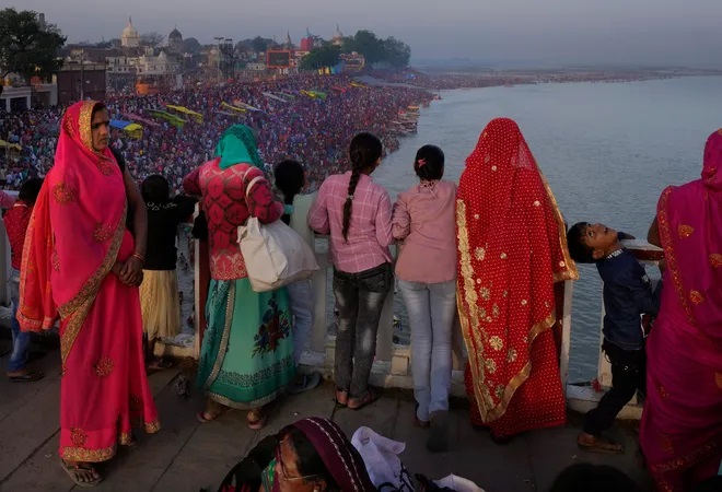 Families watch from a bridge as thousands of people enter the holy River Saryu in Ayodhya, India, Thursday, March 30, 2023. The United Nations says India will be the world’s most populous country by the end of April, eclipsing an aging China. (AP Photo/Manish Swarup)